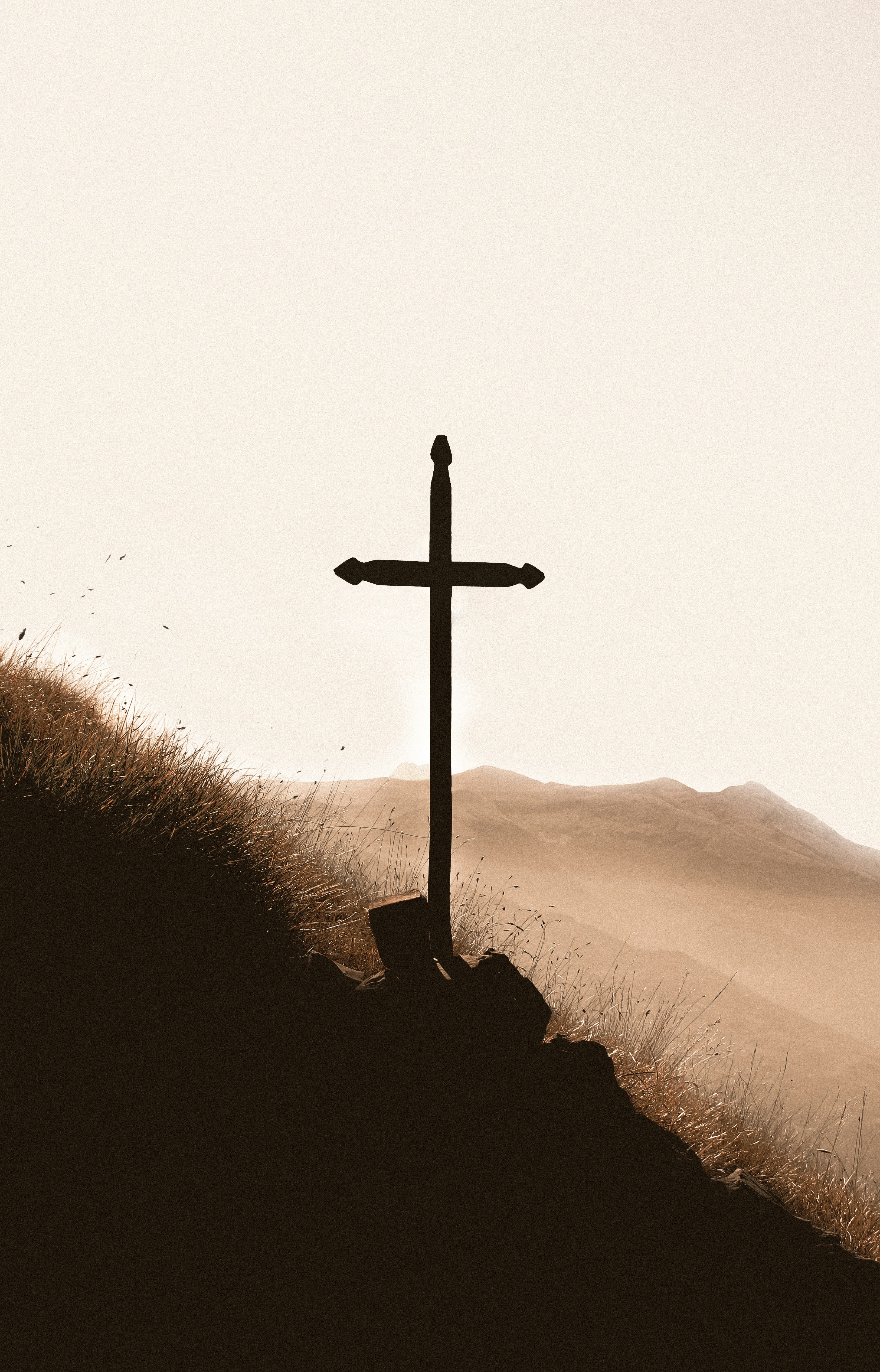 Silhouette of a cross on a hill at sunrise